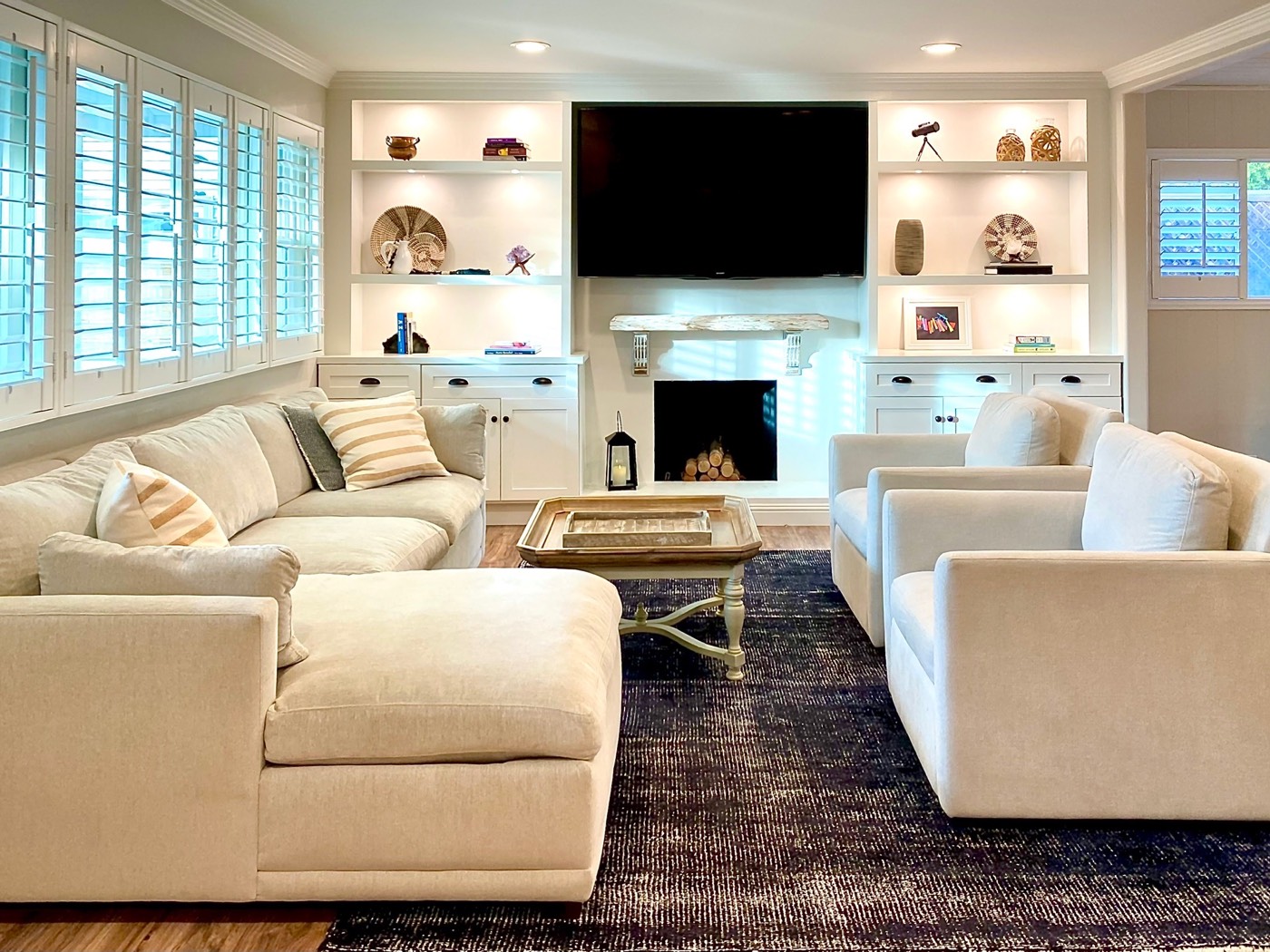 Bright living room with built-in shelving, fireplace and large windows