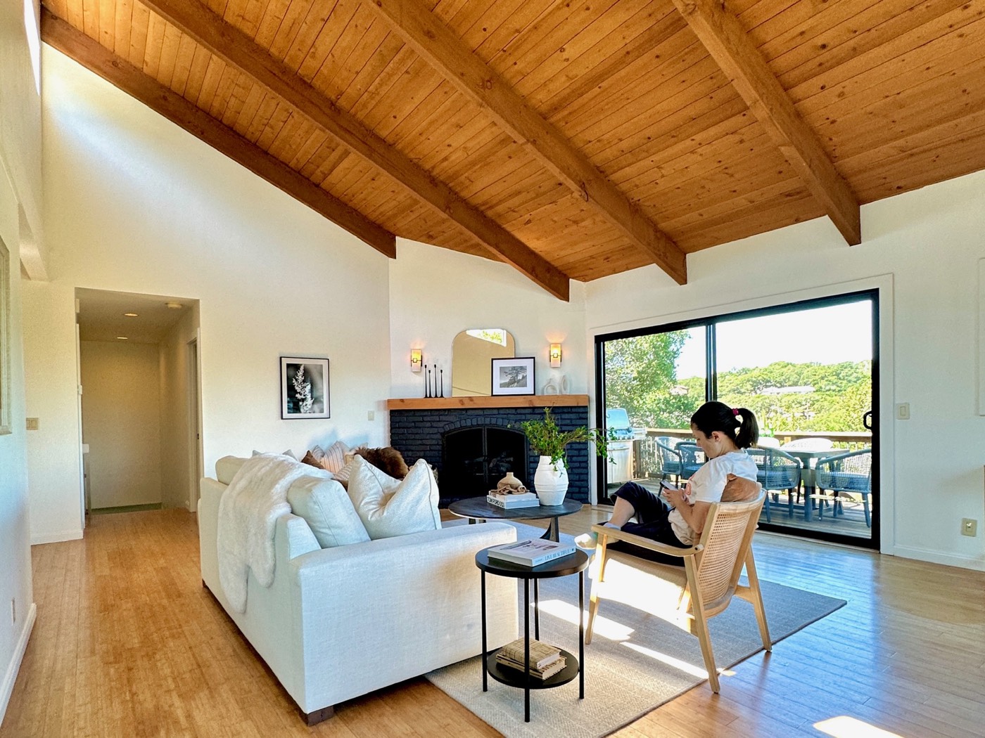 Living room with a vaulted wood ceiling, large windows and an open dining area