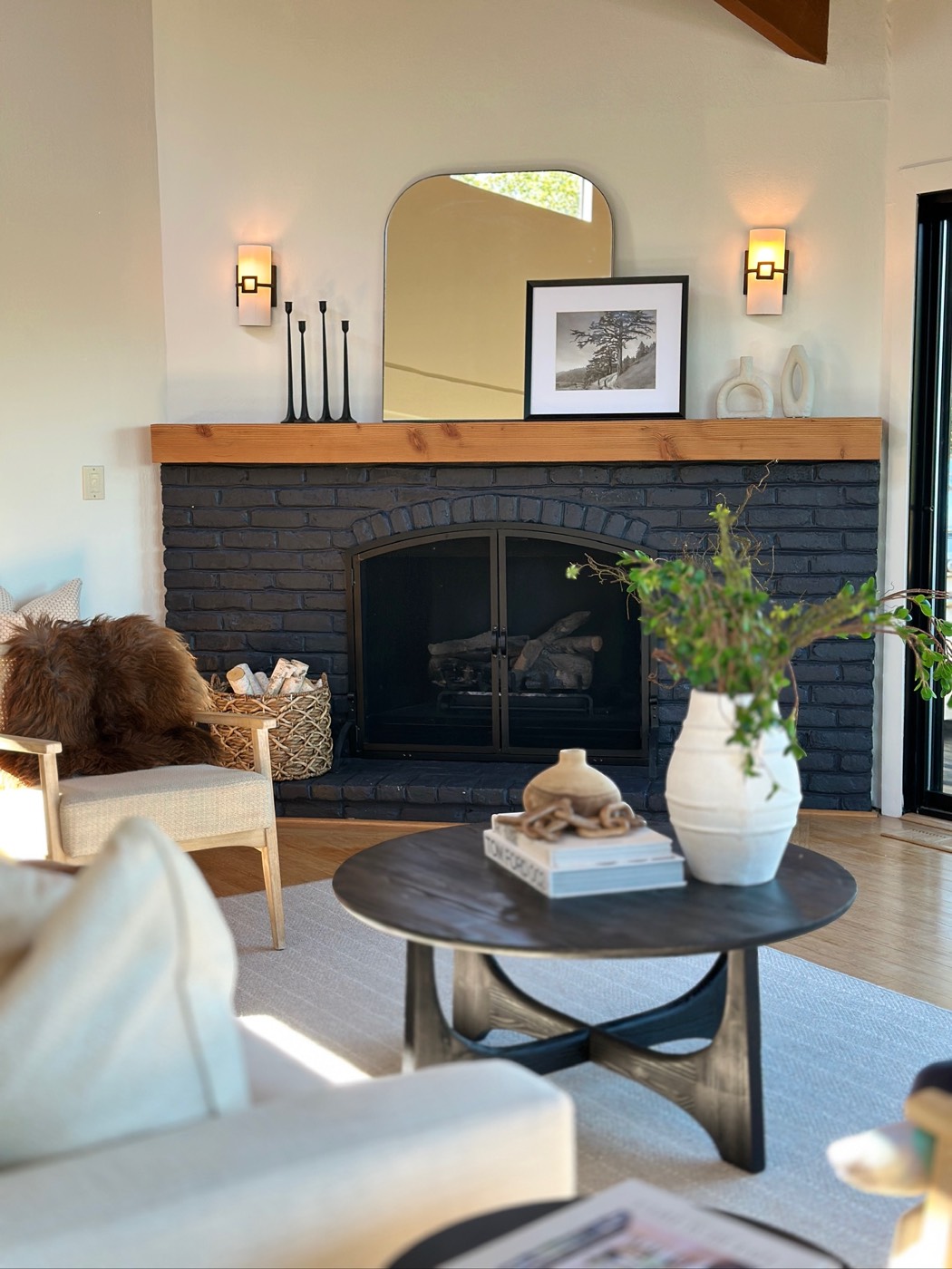 Living room with a dark fireplace, wood floors and large windows