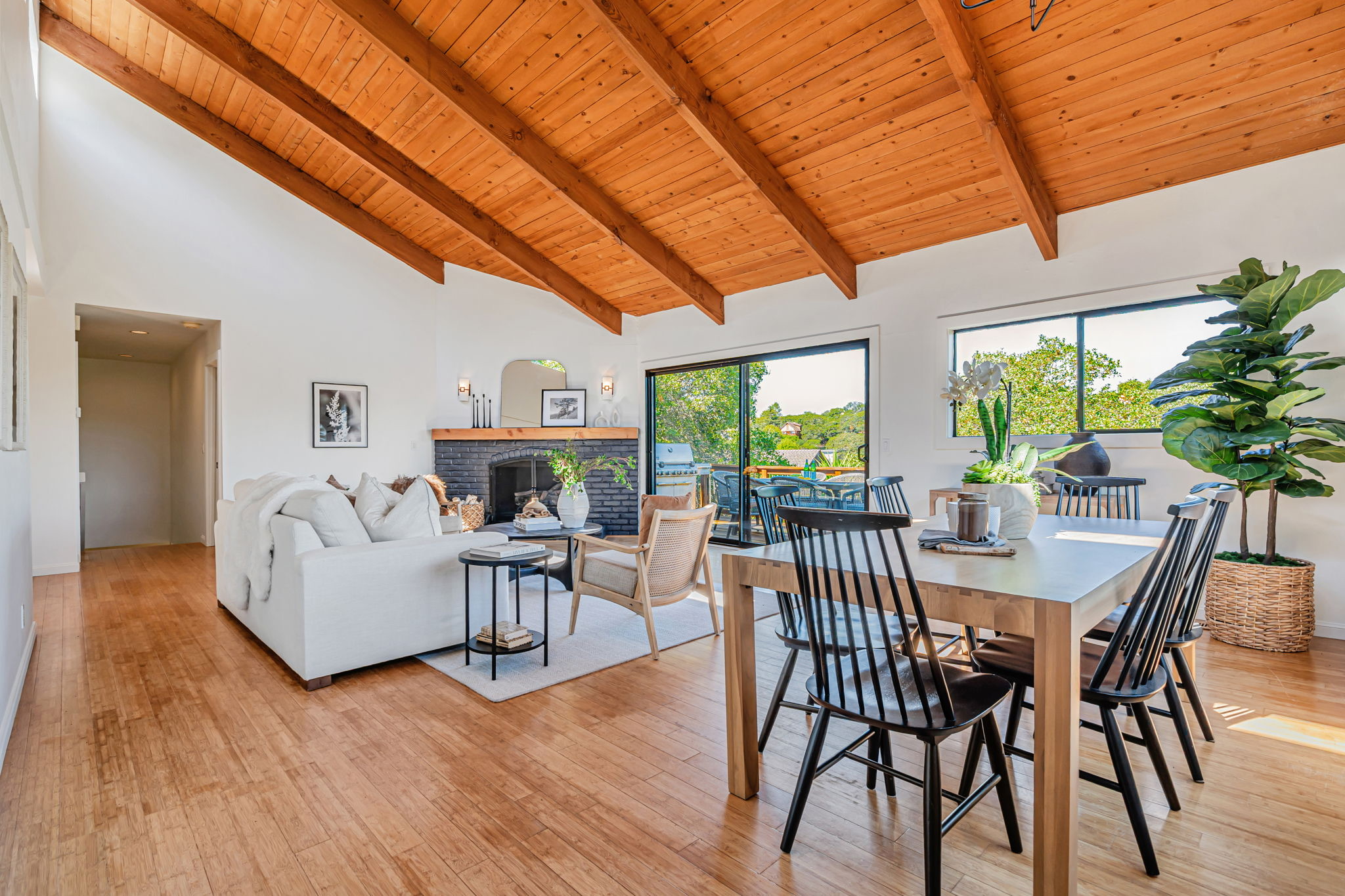 Warm open living and dining room with a wood ceiling and large windows