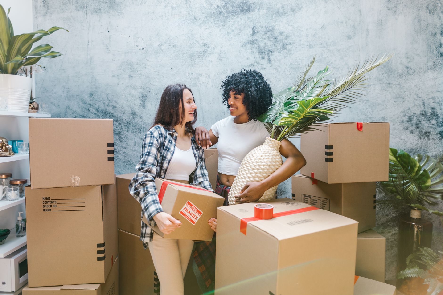 Two women unpacking boxes in their new home